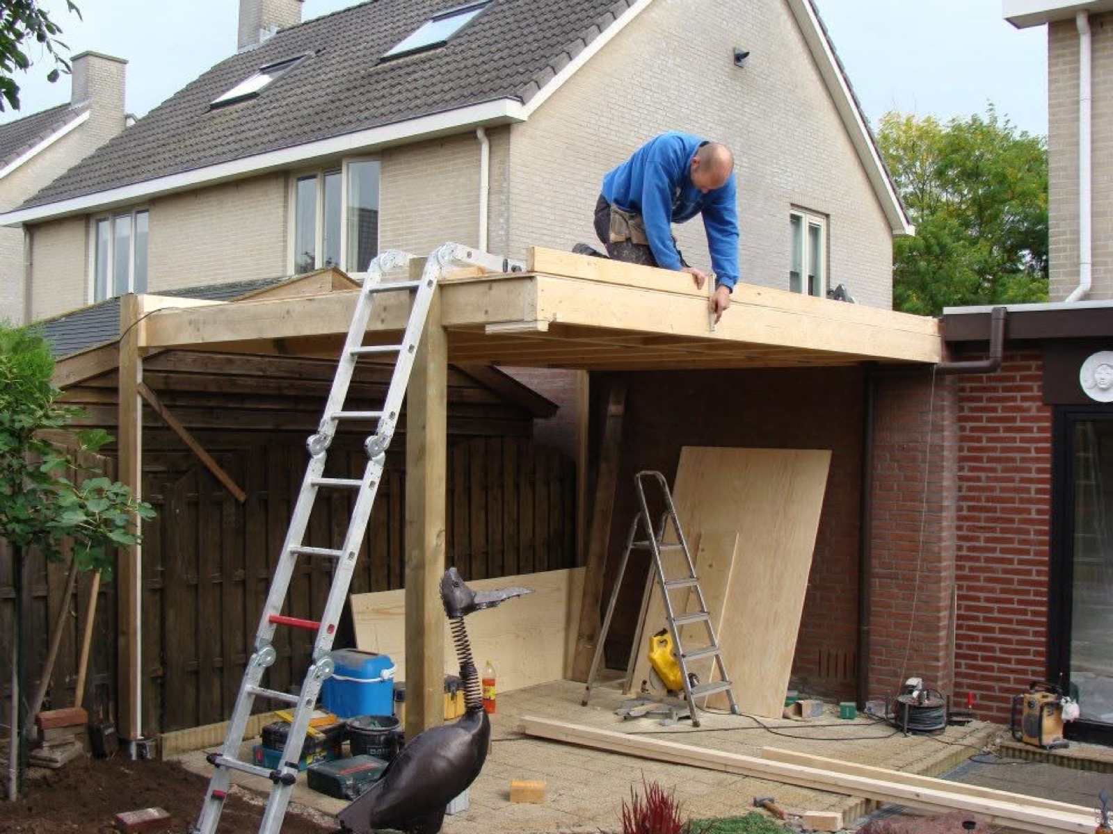 Carl Bistervelts bouwt een houten overkapping aan een woning