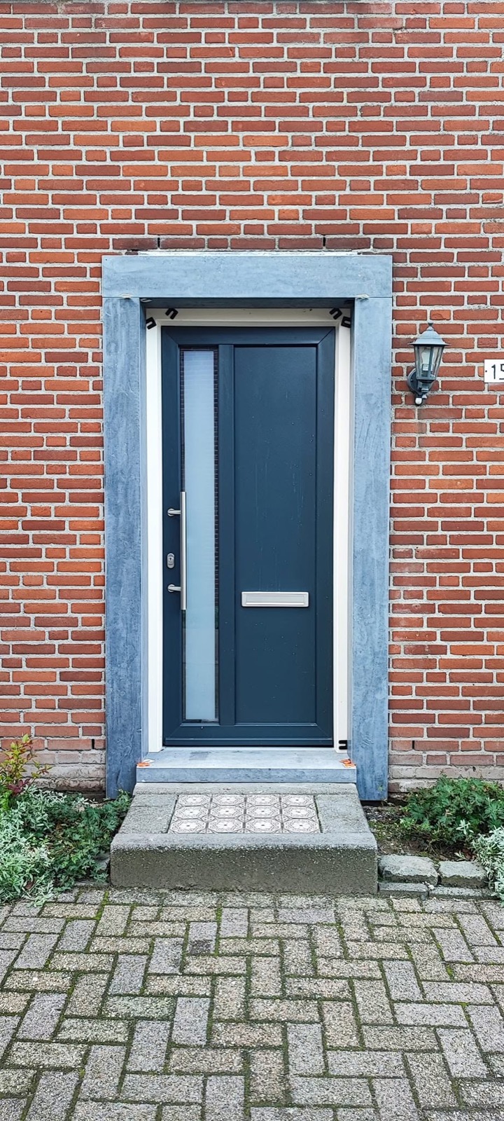 Nieuwe voordeur met kozijn in bakstenen gevel