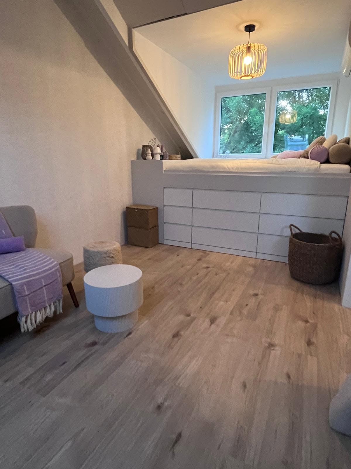 Verbouwde zolder met verhoogd bed en houten vloer